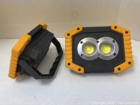 Two rechargeable LED work lamps showing front and side angles with yellow and black durable housing.