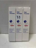 Three unopened boxes of digital thermometers standing side by side, displaying product information on the side panel.