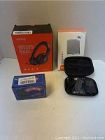 Photo showing all four electronic items including the MPOW wired headset box, TaoTronics wireless adapter box, LED string light box, and the VZ Sports Mate player with carrying case and cables.