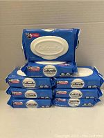 Eight packs of Cottonelle flushable wipes stacked on a cardboard surface showing brand name, packaging and quantity.