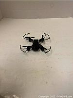 Image of the black Eachine EG1 mini drone on a plain surface, showing its quadcopter design with rotor guards.