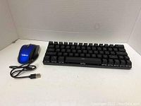 Photo of a wired compact mechanical keyboard and a wired USB mouse placed side by side on a white surface.