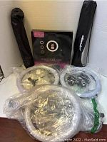 Lot includes three ring lights, two in plastic bags and one Dodocool brand ring fill light boxed, plus two tripods in black carrying cases.