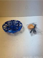 Blue spherical remote drone with protective cage and visible propellers inside