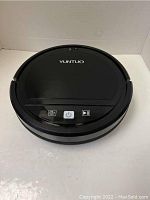 Yuntuo black smart robot vacuum cleaner on white surface showing top controls and brand.