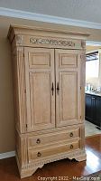Front view of solid oak armoire showing the carved details on top, two doors, and two drawers below