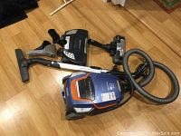 Overview of canister vacuum, flexible hose, telescoping wand, and two floor heads