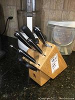 Full view of the wooden knife block with five knives inserted, showing Henckels logo and wear.
