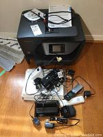 HP OfficeJet Pro 6960 printer with touchscreen, three VTech cordless phones and assorted chargers on wooden floor