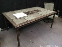 Full view of rectangular metal table showing mixed tile, stone panels, and decorative metal center insert on tabletop