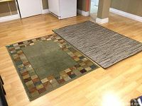 Two throw rugs lying flat on a light wood floor showing colors, size and pattern.
