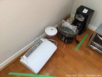 Photo shows all appliances arranged on floor: vacuum sealer, food canister, food steamer, coffee maker, hand mixer.
