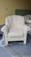 Front view of cream-colored upholstered tub chair showing shell-back and rolled arms