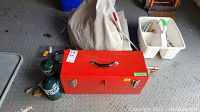 Overview photo showing the red toolbox, two green propane canisters, beige tarps folded behind them, and white gardening caddy with tools.