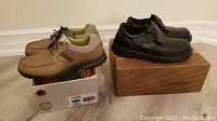 Two pairs of men's shoes placed side-by-side for comparison, tan casual sneakers on the left and black formal shoes on the right, showing shoes and their boxes