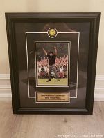 Full view of the framed 2004 Phil Mickelson Masters win photo showing black frame with plaque and logo emblem.