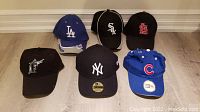 Photo showing six brand new baseball hats with MLB team logos.