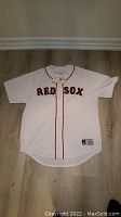 Full front view of the white Boston Red Sox Russell Athletic jersey with red piping and 'RED SOX' lettering.
