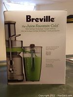 Front view of the Breville Juice Fountain Cold product box showing the juicer and large transparent green juice jug with handle, highlighting Cold Spin Technology.