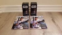 Two CC Sabathia Star Wars bobbleheads in original boxes, two Yankees magazines with CC Sabathia on the cover, and a pen arranged on the floor.