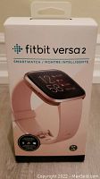 Front view of Fitbit Versa 2 retail box featuring image of smartwatch with pink band and key features displayed.