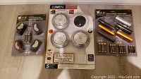 Shows three packages: one of 4 wireless wall lights with one light removed, one sealed 4-pack wireless wall lights, and one sealed 3-pack LED headlamps with batteries