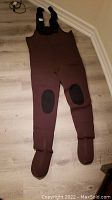 Full view of brown neoprene hip waders with attached foot covers and black knee reinforcement patches.