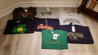 Seven assorted new with tags collegiate-themed shirts including Miami Hurricanes and Notre Dame