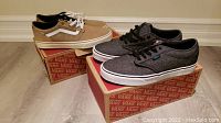 Two pairs of Vans shoes on their boxes: tan/beige and gray color, both men size 9.