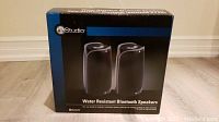 Front view of Instudio water resistant Bluetooth speakers box showing image of speakers and brand name.