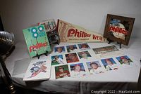 Full overview of all seven items including the framed mirror wall hanging, pennant, team and player prints, and three publications arranged on a white backdrop.