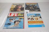 Four Beatles-related vintage magazines displayed on a white surface, including Life, People Weekly, Rolling Stone, and a Rolling Stone Beatles anniversary issue.
