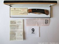 Original box opened showing knife and paper inserts including certificate, message, and care instructions.