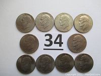 Ten Eisenhower dollar coins arranged with obverse sides visible showing Eisenhower profiles and dual dates 1776-1976, coins exhibit some wear.