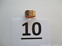 Front view of gold wedding band placed above a reference card marked ‘10’.