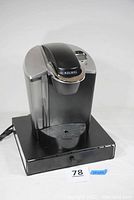 Keurig B60 coffee maker on black square base with power cord visible.
