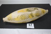 Top and side view of the ceramic fish-shaped cooker showing yellow and olive green fish patterns on cream base.