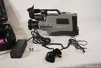 Panasonic AG-456UP camcorder with attached cables and charger visible on neutral background