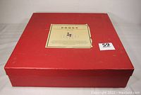Closed red box with original Prost chess set label attached to top, with slight wear on label edges.