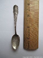 Front side of the sterling silver souvenir spoon alongside a ruler showing length near 4 inches and visible Native American figure on the handle.