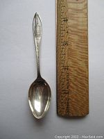 Full view of the 4.25 inch sterling silver spoon with a wooden ruler for size reference