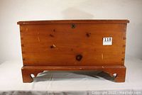 Front view of vintage cedar chest showing wood finish, keyhole, dovetail corners, and general wear.