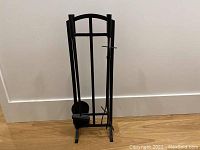 Black coated metal fire tool set with stand, including poker, brush, shovel, and tongs