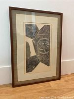 Full view of the framed abstract art print leaning against a wall on a wooden floor.