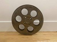 Front view of the metal film reel wall art showing circular design with six holes and central hub detail.