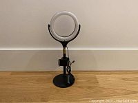 ErgoPixel ring light on adjustable stand with phone holder placed on wood floor.