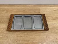 Top-down view of teak serving platter fully assembled with three stainless steel dishes in place showing tray and dish layout.