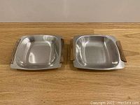 Top view of two square stainless steel serving dishes with teak wood handles, showing overall shape and condition.