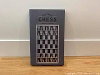 Front view of unopened vertical chess game box showing image of game board and pieces.