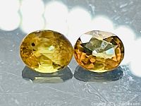 Two oval cut yellow natural sapphires, side by side showing color and clarity details.